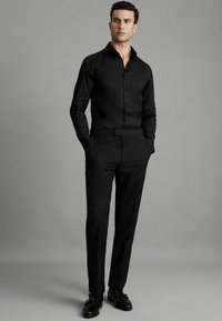 Cămașă neagră cu un design elegant, manșete lungi și o textură netedă. Asortată cu pantaloni negri personalizați și pantofi de dress lucioși.