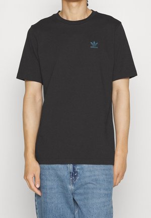 T-shirt en coton noir à manches courtes et col rond. Présente un petit logo Adidas bleu sur la poitrine, associé à un jean en denim bleu clair.