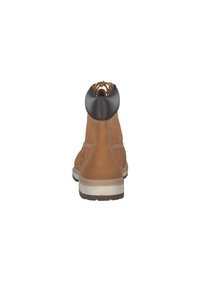 Botín de ante marrón con suela beige, que presenta un suave collar de cuero negro y cordones amarillos. Detalles de costura sencillos en la parte superior.