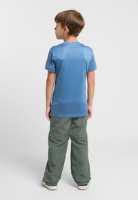 Hellblaues kurzärmliges Hemd aus glattem Stoff, kombiniert mit lockeren, hellgrünen Hosen, die mit einem gestickten Design versehen sind.