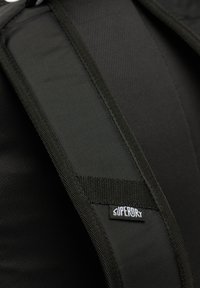 Schwarzer gepolsterter Rucksackgurt mit strukturiertem Stoff, verstärkten Nähten und gut sichtbarem "Superdry"-Logoschild. Anpassungen und Konturen verbessern die Passform.