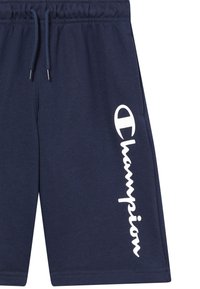 Shorts bleu marine à cordon de serrage avec le logo "Champion" blanc en vertical sur une jambe et des poches latérales.