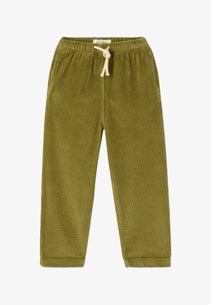 Mladé dieťa so svetlohnedými vlasmi, oblečené v žltej kapucni, olivovo zelených kordurových nohaviciach a bielych teniskách na jednoduchom pozadí.