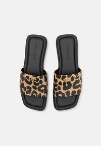 Leopard print slide sandals with a beige upper, black sole, gold hardware accent, and rectangular shape. Textured fabric, open toe design.