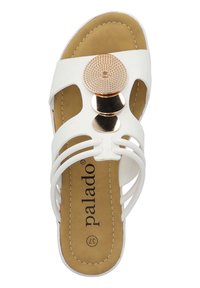 Sandalo bianco con un complesso accento circolare metallico, dotato di una soletta imbottita color marrone e un design a strappi con dettagli intagliati.