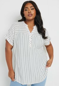 Camicia bianca con bottoni caratterizzata da sottili righe verticali nere, colletto a scollo a V, maniche corte arrotolate e vestibilità morbida. Tessuto texturizzato.