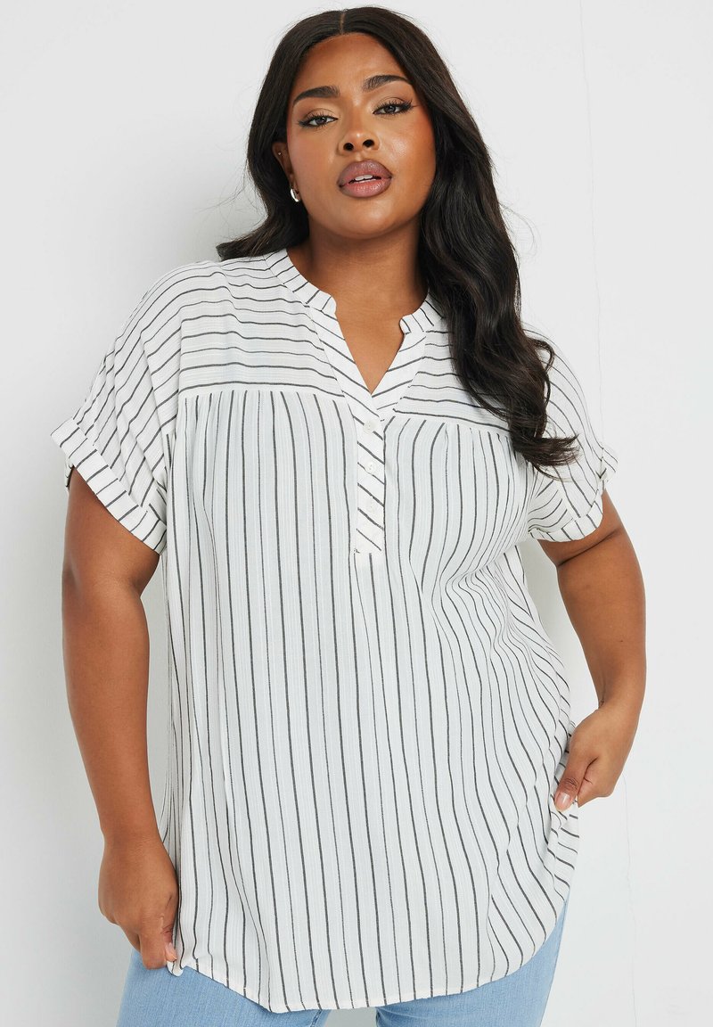 Camicia bianca con bottoni caratterizzata da sottili righe verticali nere, colletto a scollo a V, maniche corte arrotolate e vestibilità morbida. Tessuto texturizzato.