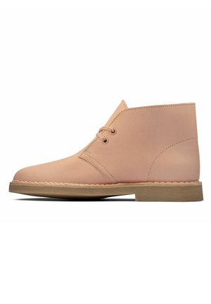 Botte de désert en cuir fauve avec deux œillets, semelle beige et coutures minimalistes, vue de profil sur fond blanc.