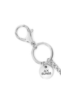 Portachiavi in metallo argentato con moschettone, anello circolare e targhetta incisa con il logo "ΔX SUN68". Finitura lucida, texture liscia.