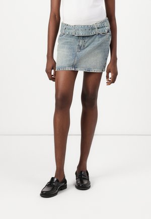 Blue denim mini skirt featuring a belt with a metallic buckle and eyelets. The fabric has a light wash and a smooth texture.