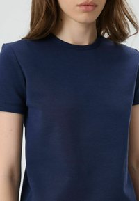Marineblauw katoenen T-shirt met korte mouwen, ronde hals, naadloze afwerking, gladde textuur en een aansluitend ontwerp.