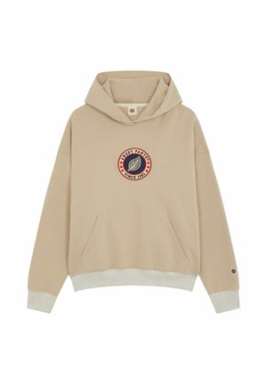 Hoodie beige avec une grande poche avant, présente un logo circulaire "Sweet Pants" en bleu marine et rouge. Poignets et ourlet en côtes de couleur gris clair.