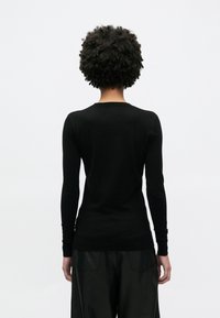 Μαύρο, εφαρμοστό πουλόβερ με μακριά μανίκια από απαλό υλικό, με στρογγυλή λαιμόκοψη και ριμπ μανσέτες, εμφανιζόμενο από πίσω.