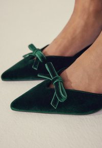 Balerini verzi din catifea, cu vârf ascuțit și o fundă decorativă pe fiecare pantof, având un design cu decupaje pe lateral și o textură netedă.