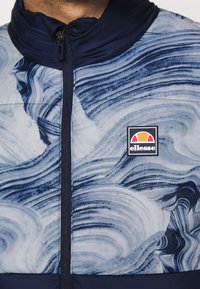 Námořnická bunda s vířivými modro-bílými vzory, hladká textura, přední zip a čtvercové logo Ellessee na hrudi.