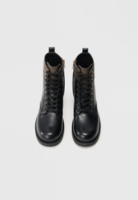 Bottines noires en cuir avec lacets, dotées d'un panneau texturé brun et de zips dorés sur les côtés. Finition lisse avec des semelles durables.