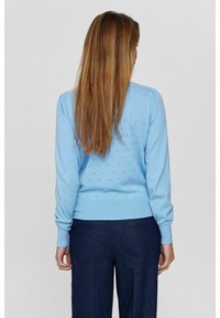 Gaiši zils adīts džemperis ar apaļu kakla izgriezumu un garām piedurknēm, ar nelielu caurumiņu rakstu un ribotām piedurknēm un apakšmalu.