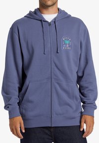 Sudadera con cremallera de tejido suave en color azul, con un estampado de logotipo que incluye una palmera. Cuenta con capucha ajustable con cordón y bolsillos frontales.
