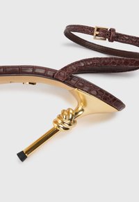 Brun læder ankelrem sandal med krokodilletekstur, prydet med en guldknot detalje på hælen og en lille sort spids på stilettoen.