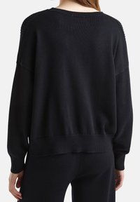 Czarny dziany sweter o luźnym kroju, z prążkowanymi mankietami i krawędzią, z fakturowanymi detalami na ramionach i szerokim dekoltem.