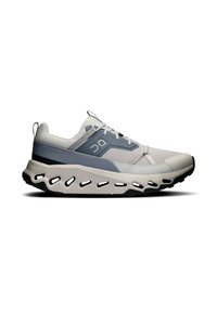 Zapatilla deportiva ligera con parte superior de malla gris y blanca, suela acolchada gruesa con detalles recortados y acentos en negro contrastantes.