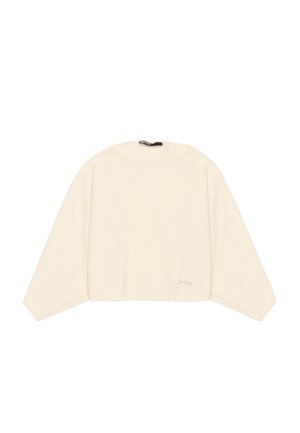 Langwerpige cropped top met lange mouwen in zachte crèmekleurige stof. Heeft een brede halslijn en een subtiele geborduurde logo aan de rechteronderzijde.