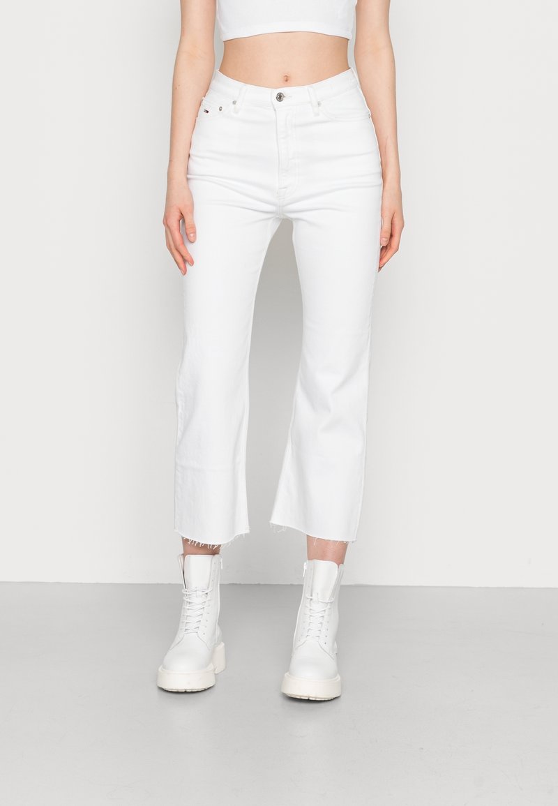 Vaqueros blancos cortos con dobladillo sin rematar, confeccionados en denim, con talle alto, diseño de cinco bolsillos y combinados con botas blancas de cordones.