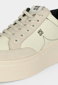 Κρέμ και μπεζ sneaker από σουέτ με παχιά ραβδωτή σόλα, σχεδιασμό με κορδόνια και λογότυπο "HUGO" στη γλώσσα και στην πλευρική επιφάνεια.