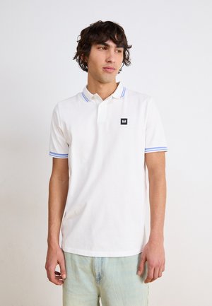 White polo shirt with blue-striped collar and cuffs, features a small black logo patch on the left chest, made from cotton fabric.