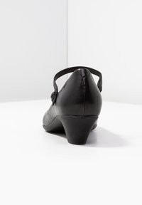 Zwarte leren hak schoen met een ronde neus en een verstelbare enkelband. Lichtjes gestructureerd oppervlak en een lage, brede hak.