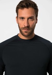 Schwarzes sportliches Langarmshirt mit rundem Halsausschnitt und nahtlosem Schulterdesign, mit einem dezenten Logo auf der Brust.