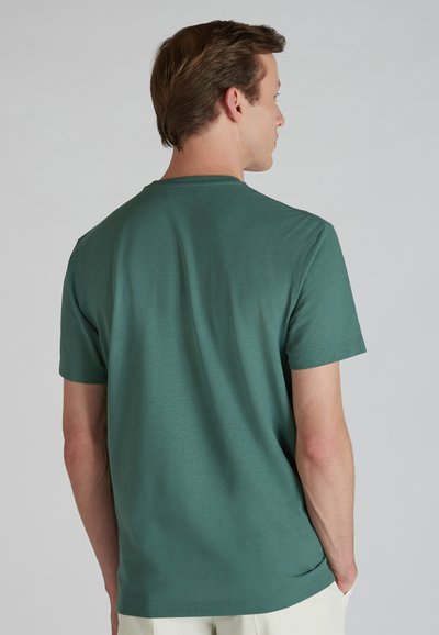 T-shirt di cotone teal con maniche corte e colletto a giro. Texture liscia, cuciture minime e vestibilità comoda, vista da dietro.