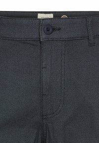 Donkerblauwe broek van een gestructureerde stof, met een enkele knoopsluiting, riemlussen en subtiele stikseldetails.