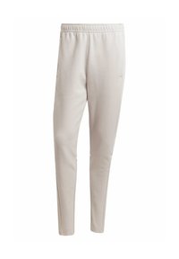 Lyse beige joggerbukser lavet af blødt stof, med elastisk talje, sidelommer og en tapered ben-design.