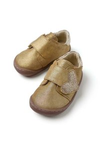 Zapatitos para toddler de cuero dorado con una cinta de velcro y un acento de corazón brillante. Punta redondeada y suave forro interior con una suela de goma marrón.