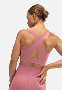 Sujetador deportivo rosa con un diseño de espalda nadadora y recorte en forma de llave. Hecho de una tela texturizada, cuenta con una banda inferior ancha para mayor soporte.