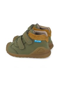 Scarpe verdi con dettagli in camoscio marrone, design chiuso, cinturini in Velcro, superficie testurizzata e suola in gomma. Presentano un'etichetta BIOtex.
