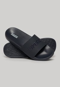 Infradito in gomma blu navy con una fascia larga che presenta il testo "SUPERDRY" in rilievo e una suola testurizzata per garantire aderenza.