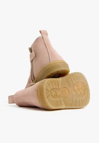 Stivaletti alla caviglia in suede rosa con zip laterale, suole in gomma testurizzata e suola esterna contrastante color tan, caratterizzati da un design robusto e cuciture minime.