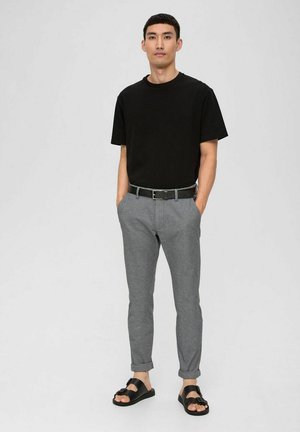 Zwarte katoenen T-shirt, lichtgrijze taps toelopende broek met een subtiel patroon, zwarte riem en zwarte sandalen met een bandontwerp.