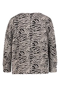 Sweter w wzór zebry w beżowo-czarnych kolorach, charakteryzujący się luźnym krojem, długimi rękawami i fakturowanym materiałem. Widok z tyłu ukazuje asymetryczny design.