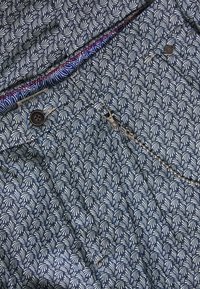 Modrý vzorovaný materiál s bílými listovitými motivy. Obsahuje zapínání na knoflík a zip s kovovým tahem. Podšitý kontrastní tkaninou.