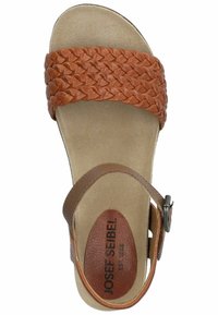 Sandal in pelle marrone con tomaia intrecciata, cinturino alla caviglia regolabile, soletta imbottita e suola liscia beige. Nome del marchio stampato sulla soletta.