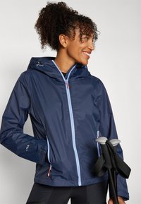 Marineblauwe waterdichte jas met lichtblauwe rits en accenten, verstelbare capuchon en zijzakken; gecombineerd met trekkingstokken.