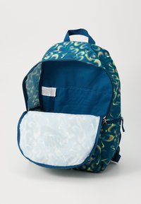 Mochila con un patrón de remolino azul y verde, con un compartimento con cremallera, bolsillo frontal de malla y material de nailon. Interior con etiqueta y tela de color azul sólido.