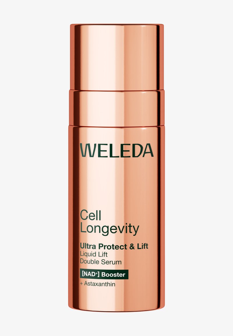 Flacon cylindrique en or rose étiqueté Weleda Cell Longevity Ultra Protect & Lift Sérum Double Lift Liquide avec booster de NAD+ et astaxanthine.