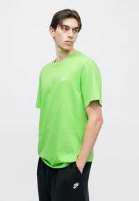 Φωτεινό πράσινο βαμβακερό T-shirt με στρογγυλή λαιμόκοψη και κοντά μανίκια, με ένα μικρό λευκό λογότυπο Nike στο στήθος.