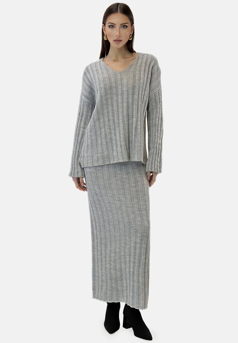 Grå ribbad stickad tvådelad outfit med en V-ringad topp och en lång kjol, som har en avslappnad passform och texturerad tyg. Svarta spetsiga stövlar fulländar looken.