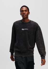 Sort, oversized sweatshirt med rund halsudsk�æring, der har hvid "KARL LAGERFELD JEANS" tekst på brystet og tekstureret stoffinish.