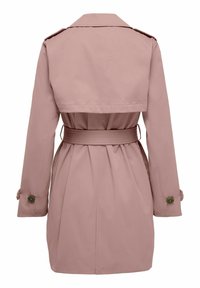 Set bagfra af en støvet lyserød trenchcoat med bredt bælte, stormklap, lange ærmer og knappede manchetter på hvid baggrund.